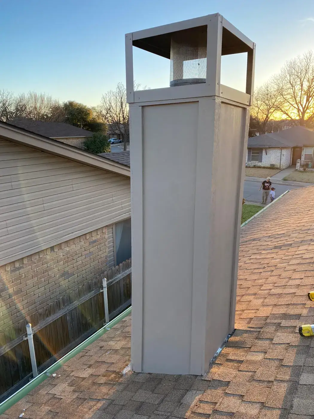 Rebuilt chimney chase with decorative shroud at sunset