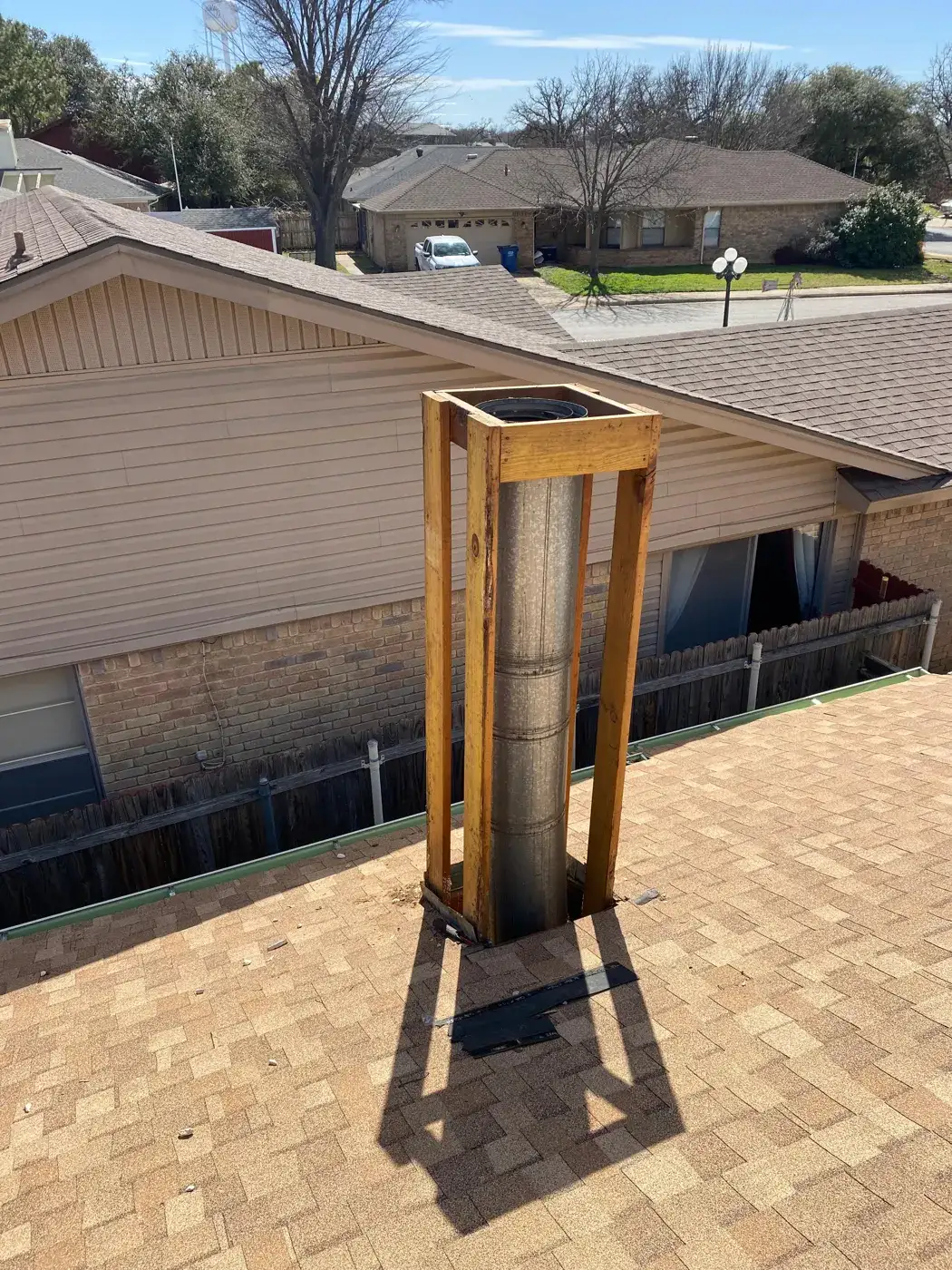 Reframed chimney chase around a stainless flue pipe on a shingle roof