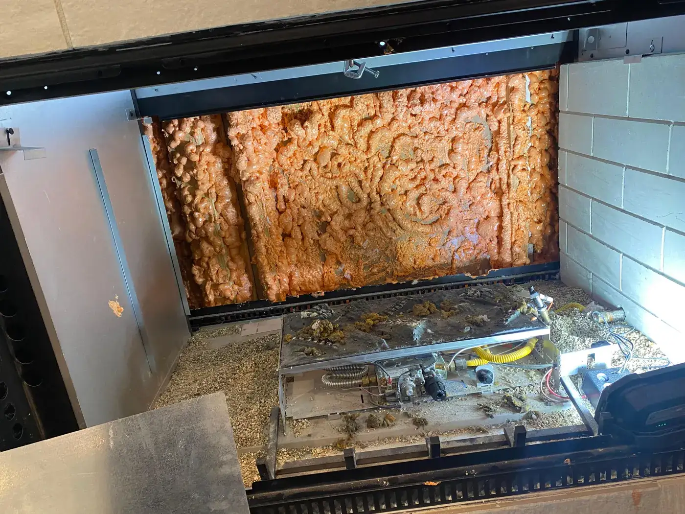 Gas fireplace with a rusted firebox panel and burner
